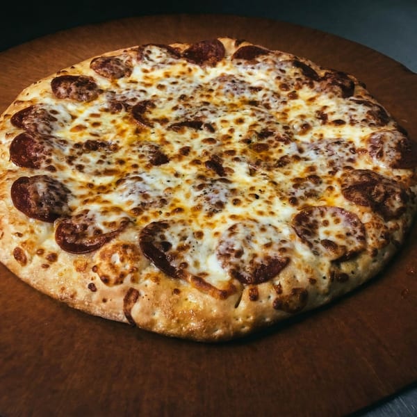 A freshly baked pepperoni pizza with melted cheese and a golden crust on a wooden peel.